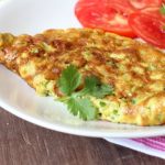 vegetable omelette on a plate with sliced tomatoes