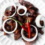 beef tapa on a plate with round onions and cayenne pepper