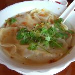 wonton soup in a bowl with parsley on top.