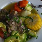 sancocho in a white bowl with spoon